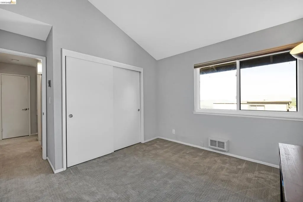Unfurnished bedroom with carpet, a closet, and vaulted ceiling