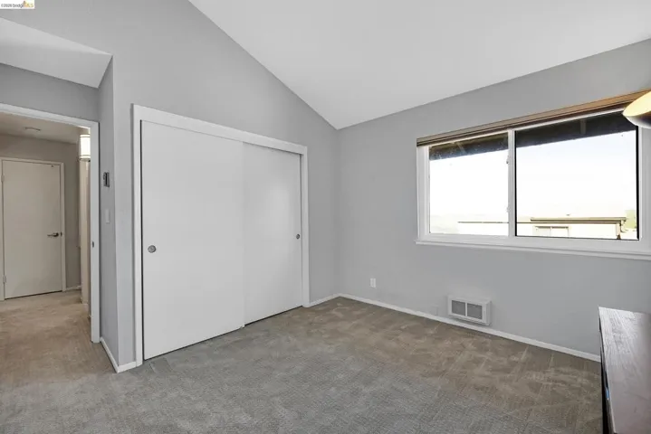 Unfurnished bedroom with carpet, a closet, and vaulted ceiling