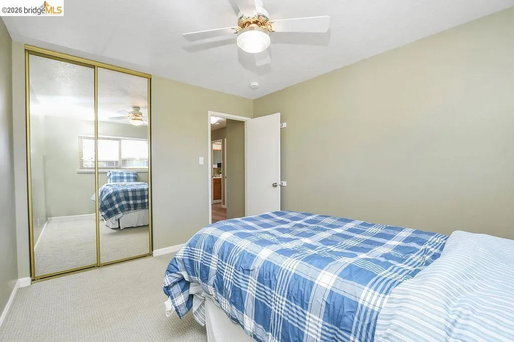 Room featuring wall-to-wall carpeting, a ceiling fan with integrated lighting, and a mirrored closet with gold-tone framing