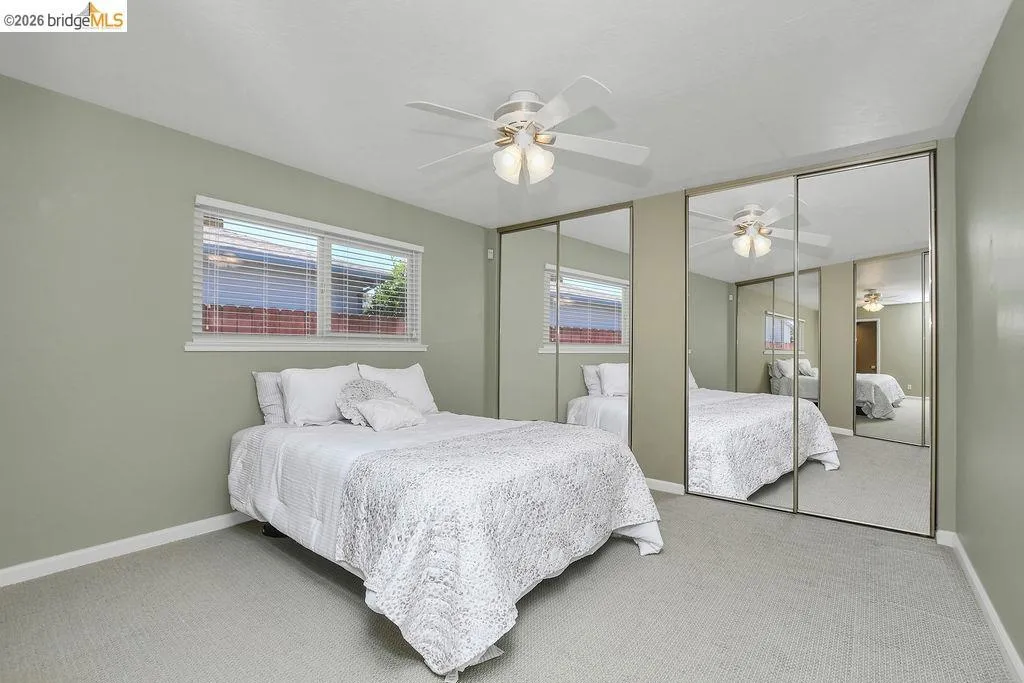 Bedroom featuring light green walls, light-colored carpeting, and a window with white blinds