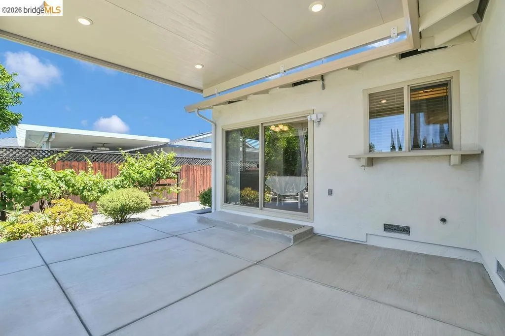 Expansive concrete patio area with a covered extension featuring recessed lighting