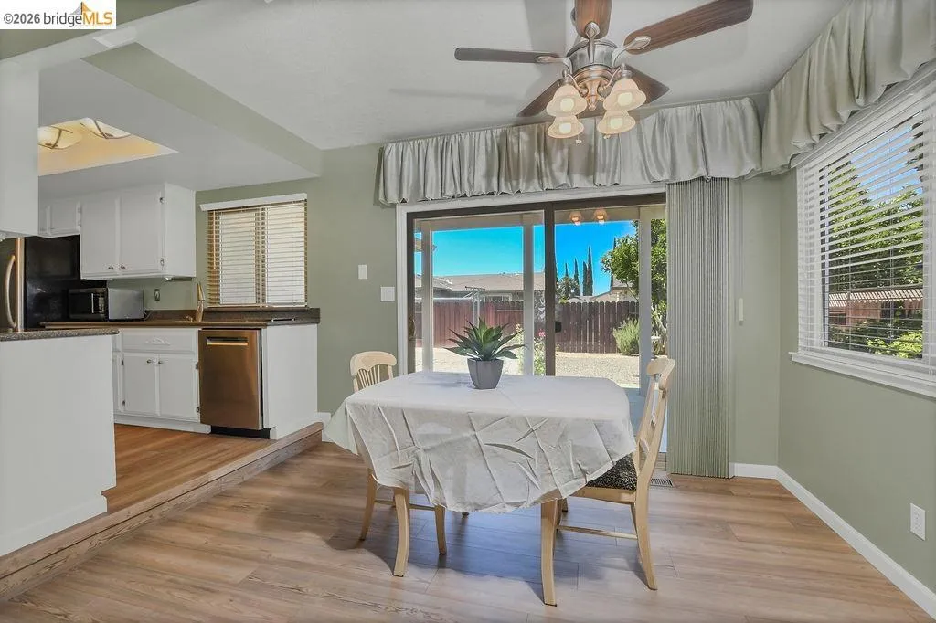 Dining area featuring wood-finish flooring, a ceiling fan with integrated lighting, and a sliding glass door to the exterior