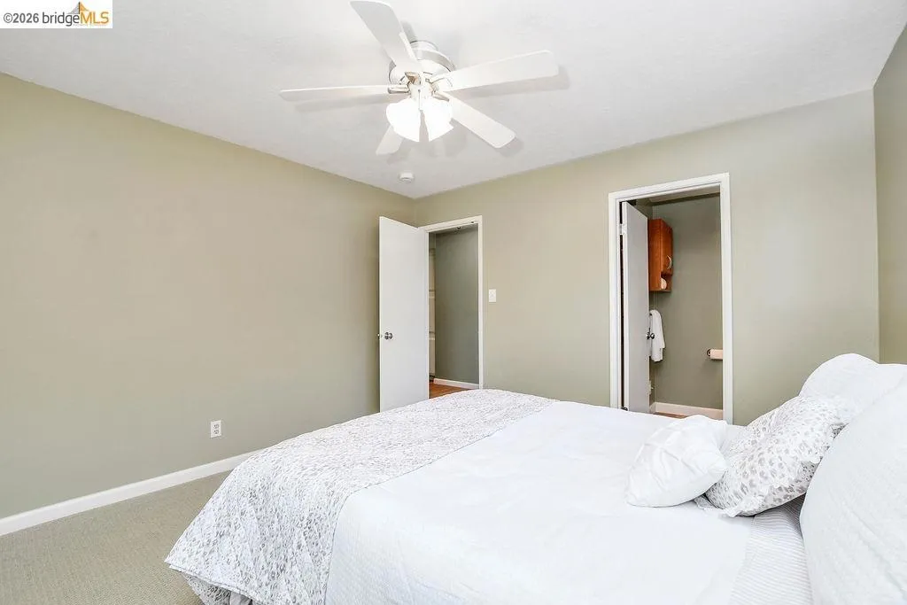 Bedroom featuring light neutral wall paint, carpet flooring, and a ceiling fan with integrated lighting
