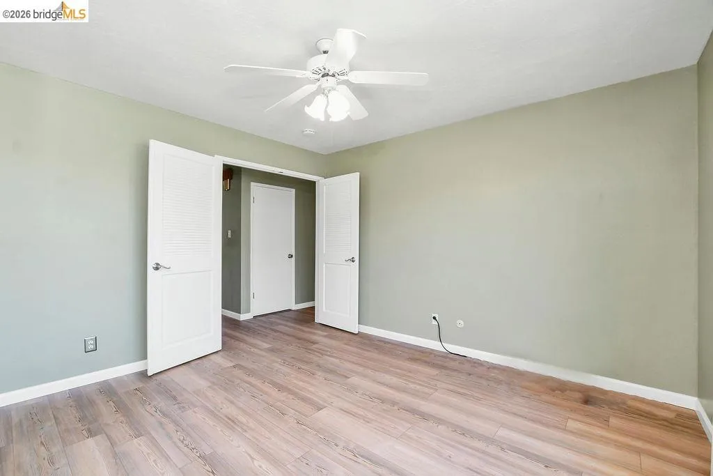 Spacious room featuring wood-finish flooring, light green walls, and white trim
