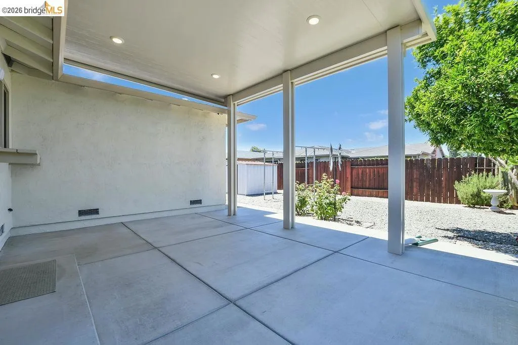 Expansive concrete patio featuring an overhead cover with recessed lighting