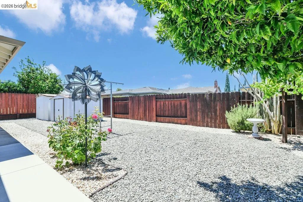 Spacious backyard featuring extensive gravel hardscaping and perimeter fencing
