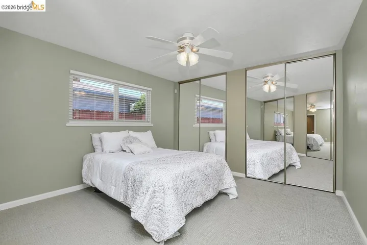 Bedroom featuring light green walls, light-colored carpeting, and a window with white blinds