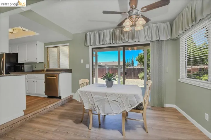 Dining area featuring wood-finish flooring, a ceiling fan with integrated lighting, and a sliding glass door to the exterior