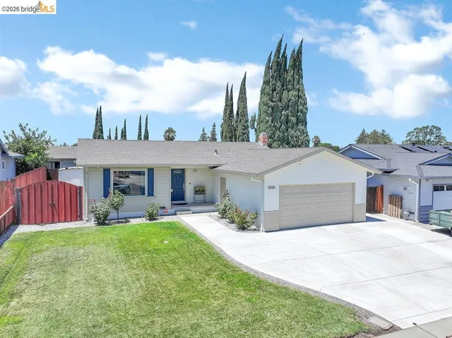 Ranch-style residence featuring a prominent garage, concrete driveway, and a manicured front lawn