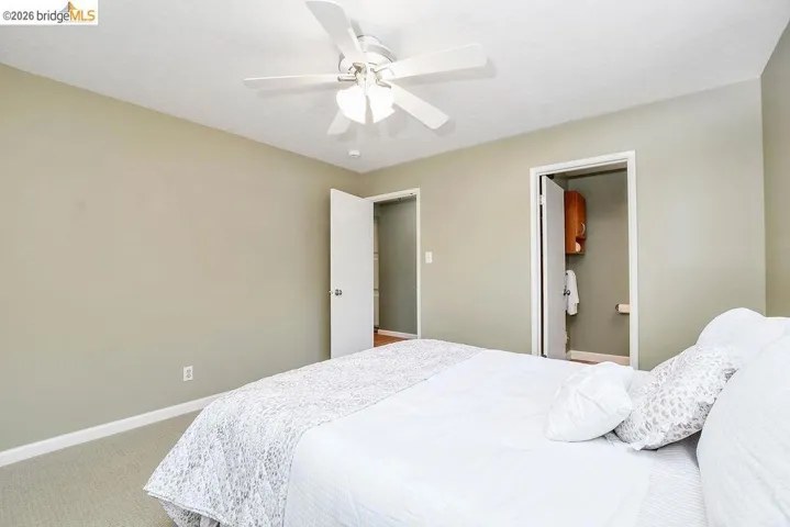 Bedroom featuring light neutral wall paint, carpet flooring, and a ceiling fan with integrated lighting