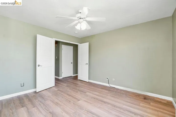 Spacious room featuring wood-finish flooring, light green walls, and white trim