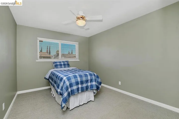 Room featuring light green walls, a window with horizontal blinds, and a ceiling fan with integrated lighting