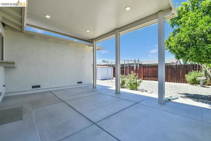 Expansive concrete patio featuring an overhead cover with recessed lighting
