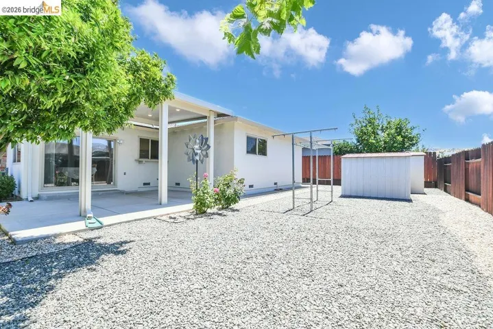 Expansive backyard featuring a gravel landscape, a covered patio with recessed lighting, and a storage shed