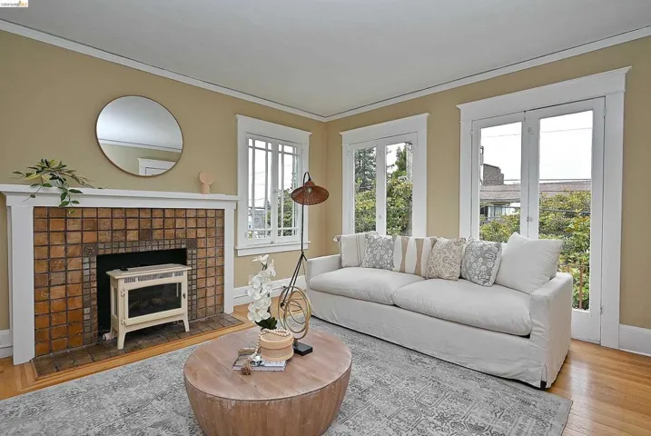 Living area featuring hardwood flooring, a tile-surround fireplace with a white mantel, and multiple windows with white trim