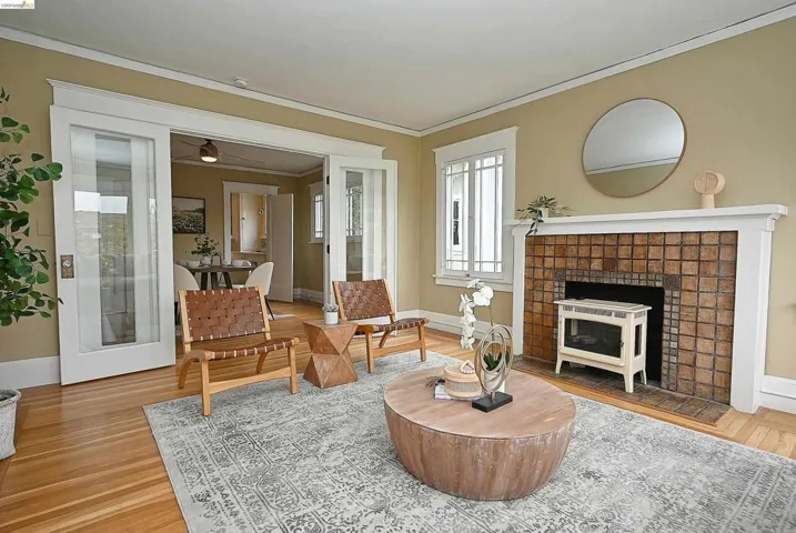 Living area featuring hardwood flooring, a tiled fireplace with mantel, and white trim