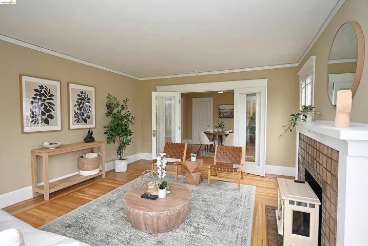Living area featuring wood-finish flooring, a fireplace with a tiled surround and white mantel, and crown molding