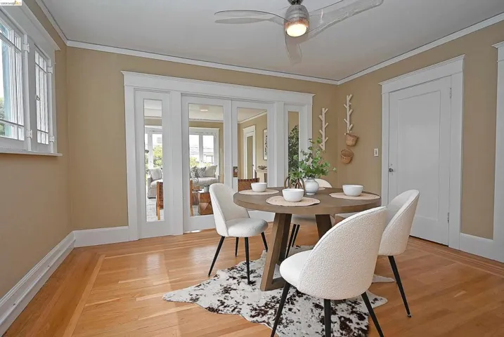 Hardwood flooring with border inlay, white trim, and a contemporary ceiling fan