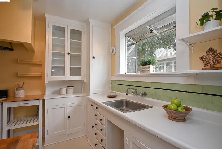 Kitchen featuring a stainless steel sink with a dual-handle faucet, white countertops, and a green subway tile backsplash