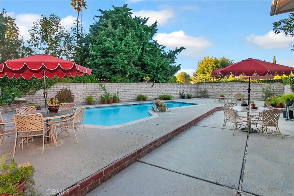 The backyard fulfills the promise of the property's exceptional setting. Framed by mature landscaping, slump stone walls, and the gentle rise of the land beyond, it feels remarkably private. The sparkling pool, expansive patios, and multiple outdoor living spaces create an inviting setting for entertaining, dining al fresco, or simply unwinding while enjoying the quiet surroundings.