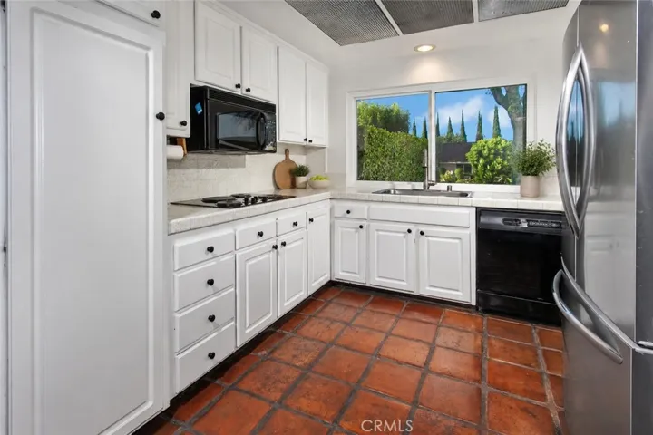 Photo is virtually staged.  Property shows as in previous photo.  The kitchen opens naturally to the informal dining area and adjoining family room, creating an inviting space where meals, conversation, and everyday life come together. It features white cabinetry, double ovens, a Frigidaire refrigerator, a pantry, a dual basin stainless steel sink, and new vinyl windows that frame neighborhood and mountain views.