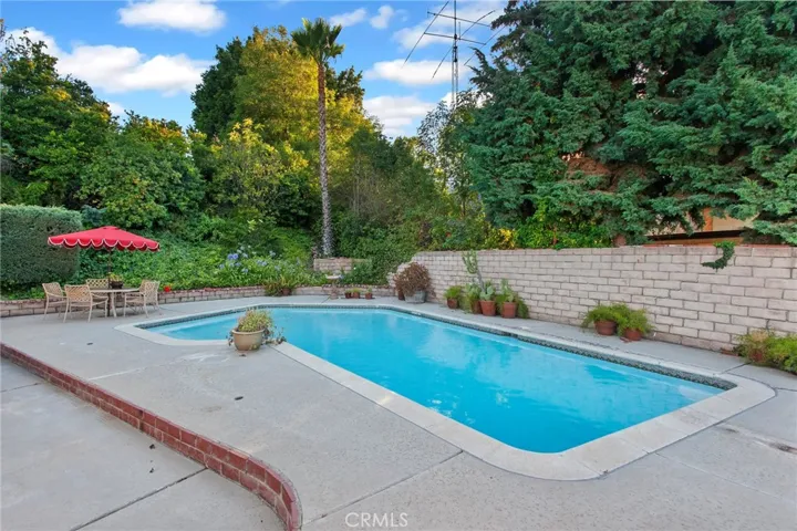 The backyard fulfills the promise of the property's exceptional setting. Framed by mature landscaping, slump stone walls, and the gentle rise of the land beyond, it feels remarkably private. The sparkling pool, expansive patios, and multiple outdoor living spaces create an inviting setting for entertaining, dining al fresco, or simply unwinding while enjoying the quiet surroundings.