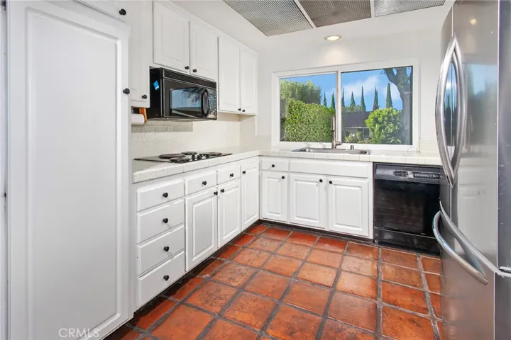 The kitchen opens naturally to the informal dining area and adjoining family room, creating an inviting space where meals, conversation, and everyday life come together. It features white cabinetry, double ovens, a Frigidaire refrigerator, a pantry, a dual basin stainless steel sink, and new vinyl windows that frame neighborhood and mountain views.