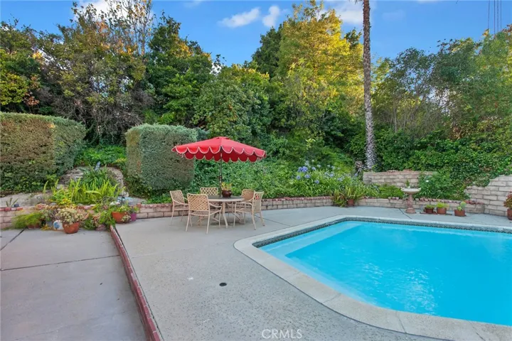 The backyard fulfills the promise of the property's exceptional setting. Framed by mature landscaping, slump stone walls, and the gentle rise of the land beyond, it feels remarkably private. The sparkling pool, expansive patios, and multiple outdoor living spaces create an inviting setting for entertaining, dining al fresco, or simply unwinding while enjoying the quiet surroundings.