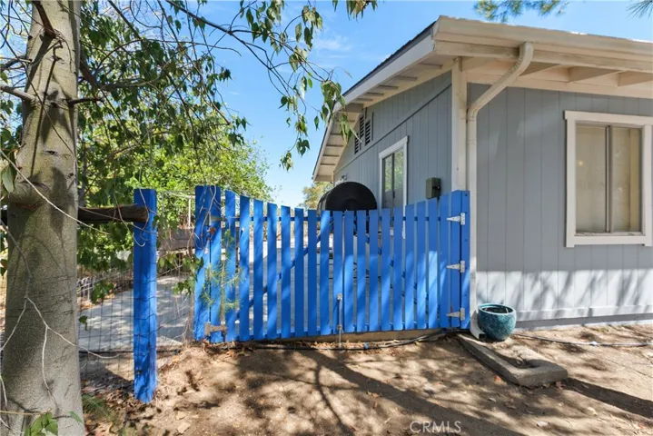 Side gate entry to the concrete patio, composting bin, a raised vegetable garden structure.