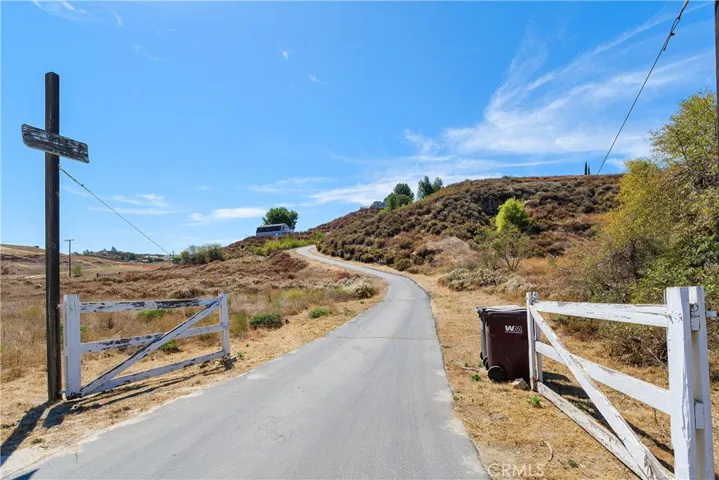 Gated entry with paved driveway to the barn/workshop and the single story home.