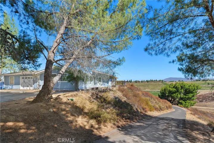 View from the top of the driveway showing the home and looking back down the paved driveway. Views abound!