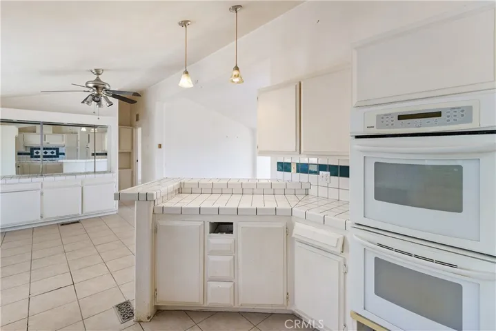 Another view in the kitchen looking into the dining room. Pendant lighting above the counter. Double ovens.