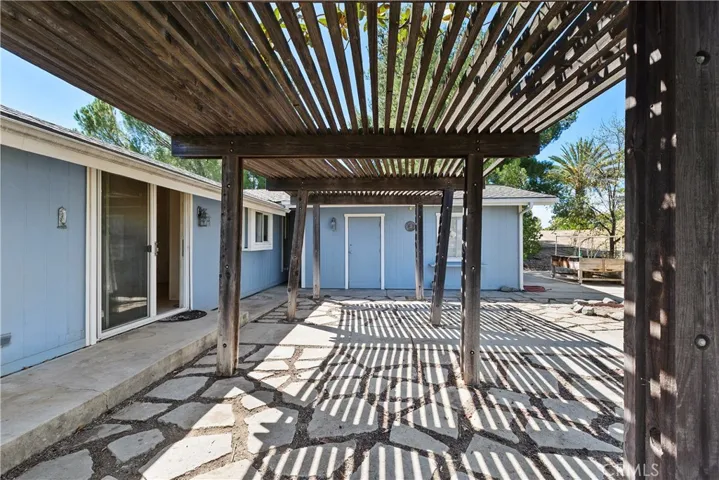 Covered wood patio off the bvack sliding doors with view to attached garage.