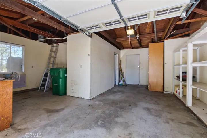 Garage is currently a 1 car garage. Area with a workbench and cabinetry. There is also a built-in pantry with pull out drawers, built-in shelving. Door to the additional room and also the outdoor patio.
