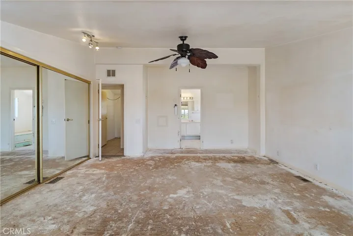 Another view of the Primary Bedroom with ceiling fan and mirrored closet doors from the retreat looking toward the primary bath.