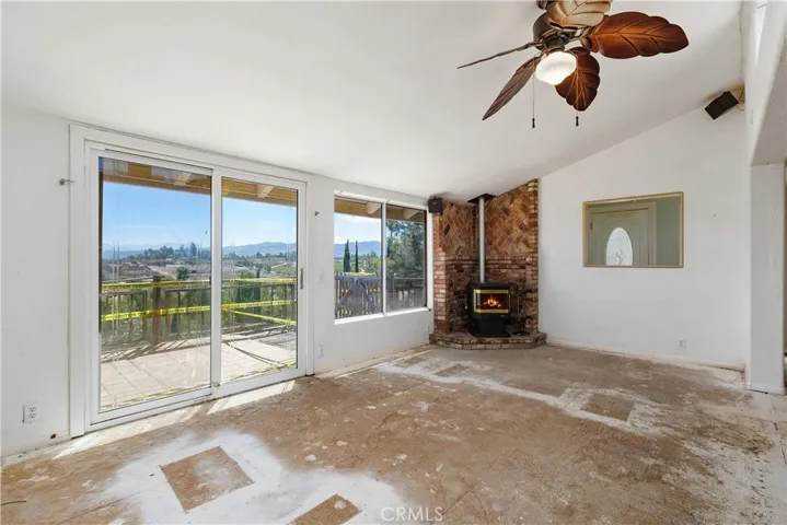 Great Room with a vaulted ceiling, brick platform for the pellet stove and sliding door to the deck with panoramic vineyard views! Decking is a safety issue in the current state so repairs or replacement will be needed.
