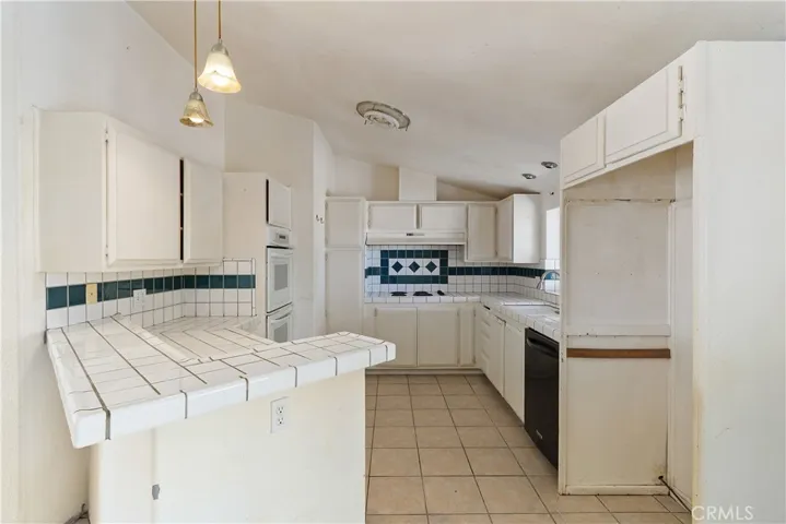 Kitchen with tile counters, garden window, electric cooktop with vent.