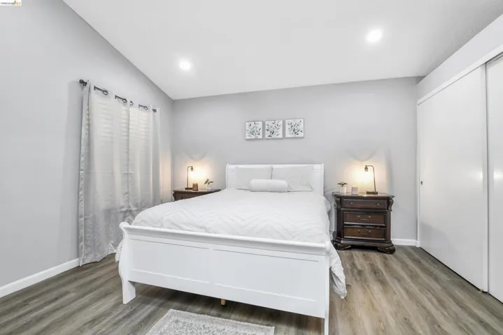 Bedroom featuring wood-finish flooring, recessed lighting, white baseboards, and a white sliding closet door