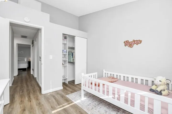 Room featuring wood-finish flooring, a built-in closet with sliding doors, and integrated shelving