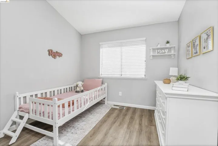 Room featuring wood-finish flooring, a window with horizontal blinds, and light gray painted walls