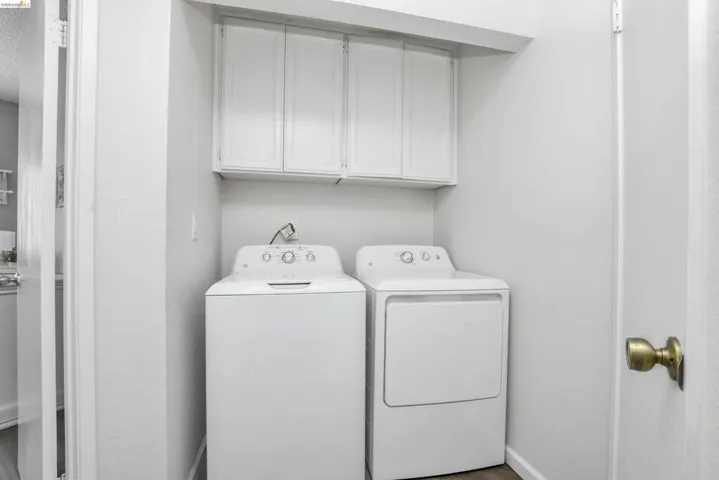 Dedicated laundry area featuring overhead white cabinetry and wood-finish flooring