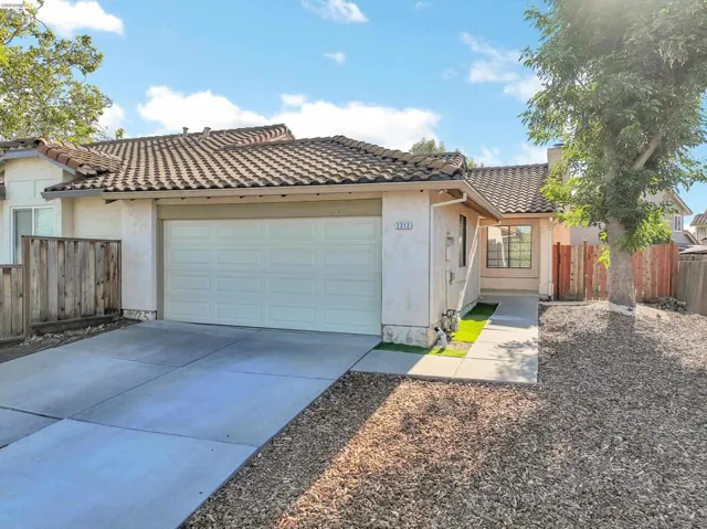 Single-story residence featuring a tile roof, an attached garage, a concrete driveway, and a wooden fence