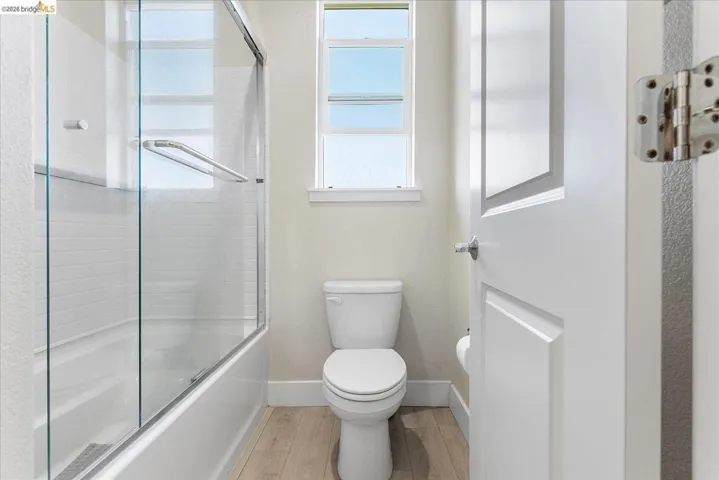 Bathroom featuring a tub/shower combination with glass enclosure, white subway tile surround, and a window