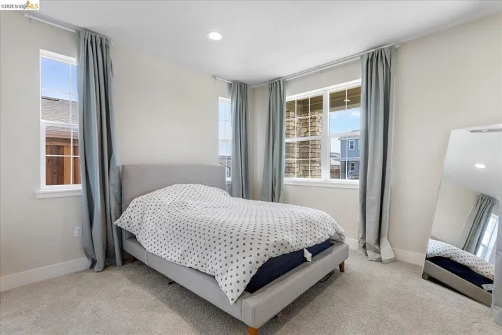 Spacious room featuring multiple large windows, recessed lighting, neutral wall tones, and plush carpeting