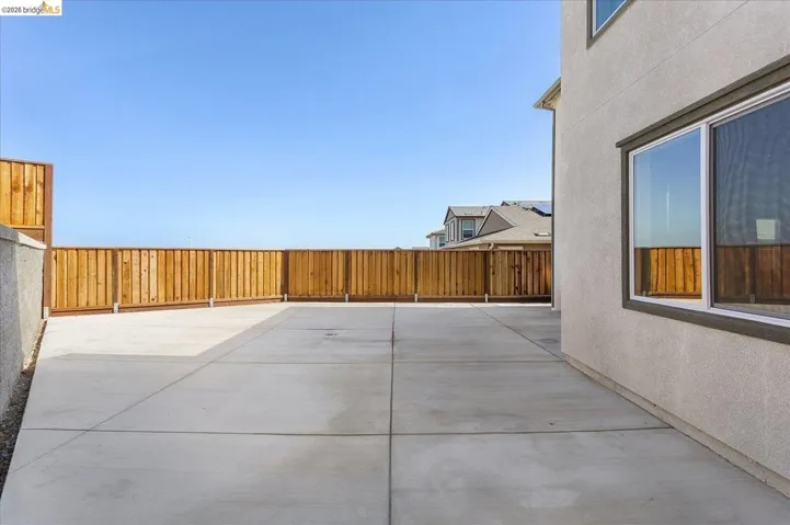 Expansive concrete patio bordered by a wood privacy fence