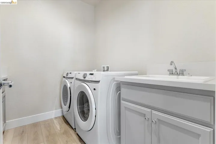Dedicated laundry area featuring wood-finish flooring
