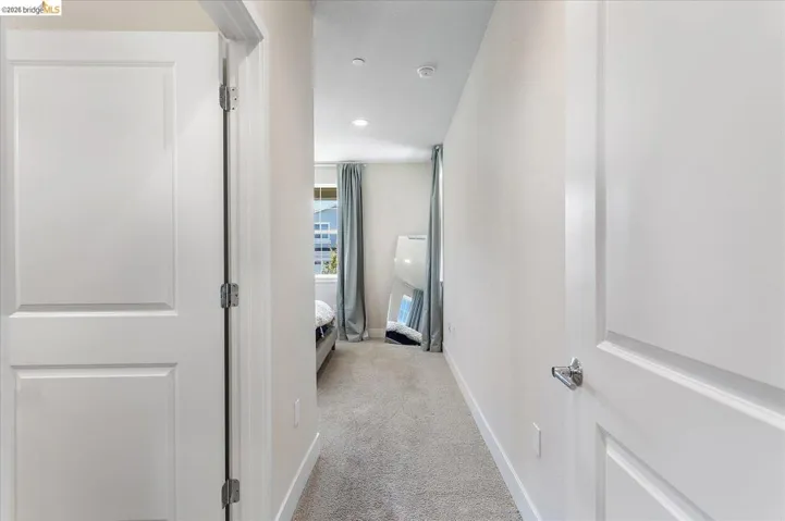 Hallway with light gray carpeting and white baseboards