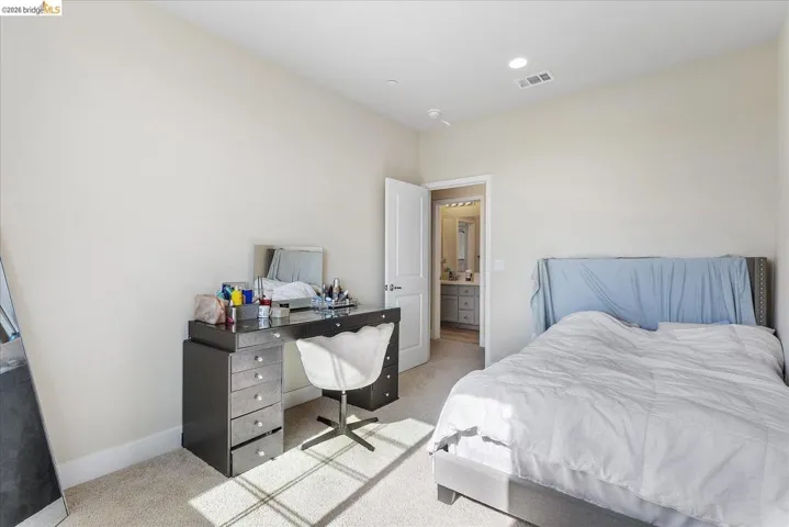 Bedroom featuring neutral carpet flooring, recessed lighting, and an entryway to an attached bathroom with a dual vanity