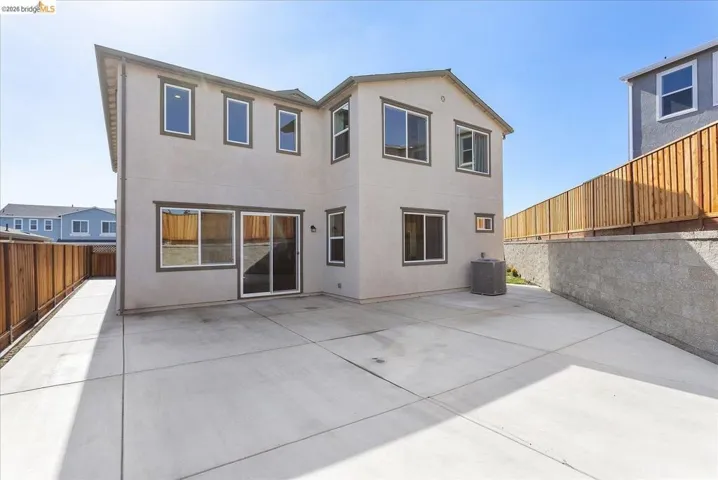 Expansive concrete patio with a two-story stucco exterior