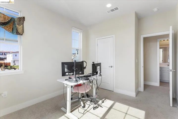 Carpeted room with two windows, recessed lighting, and a white paneled door